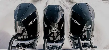 Three black motorboats speeding across the water, leaving white trails behind them