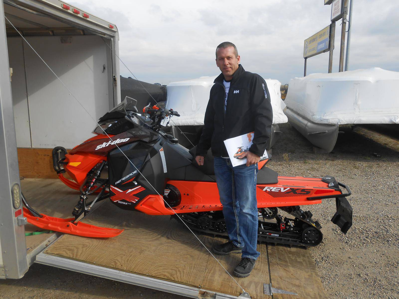 Man standing in front of an orange Ski-Doo Renegade snowmobile