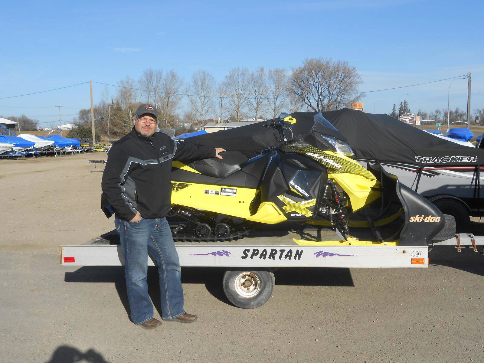 Man posing in front of a yellow Ski-Doo Rotax snowmobile.