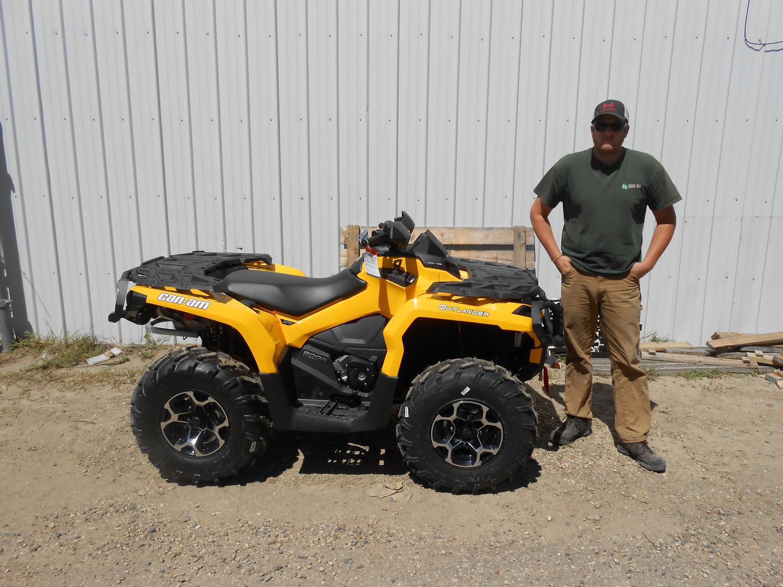 Man standing beside a yellow Can-Am Outlander ATV.