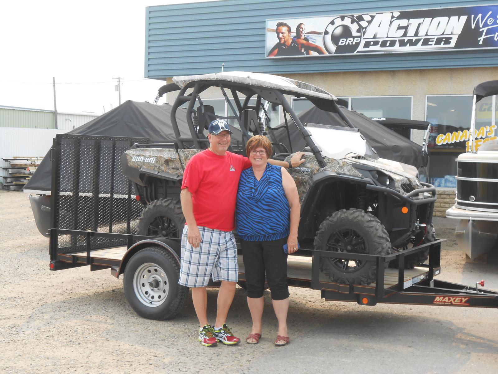 A man and a woman standing in front of a camo Can-Am Commander XT UTV