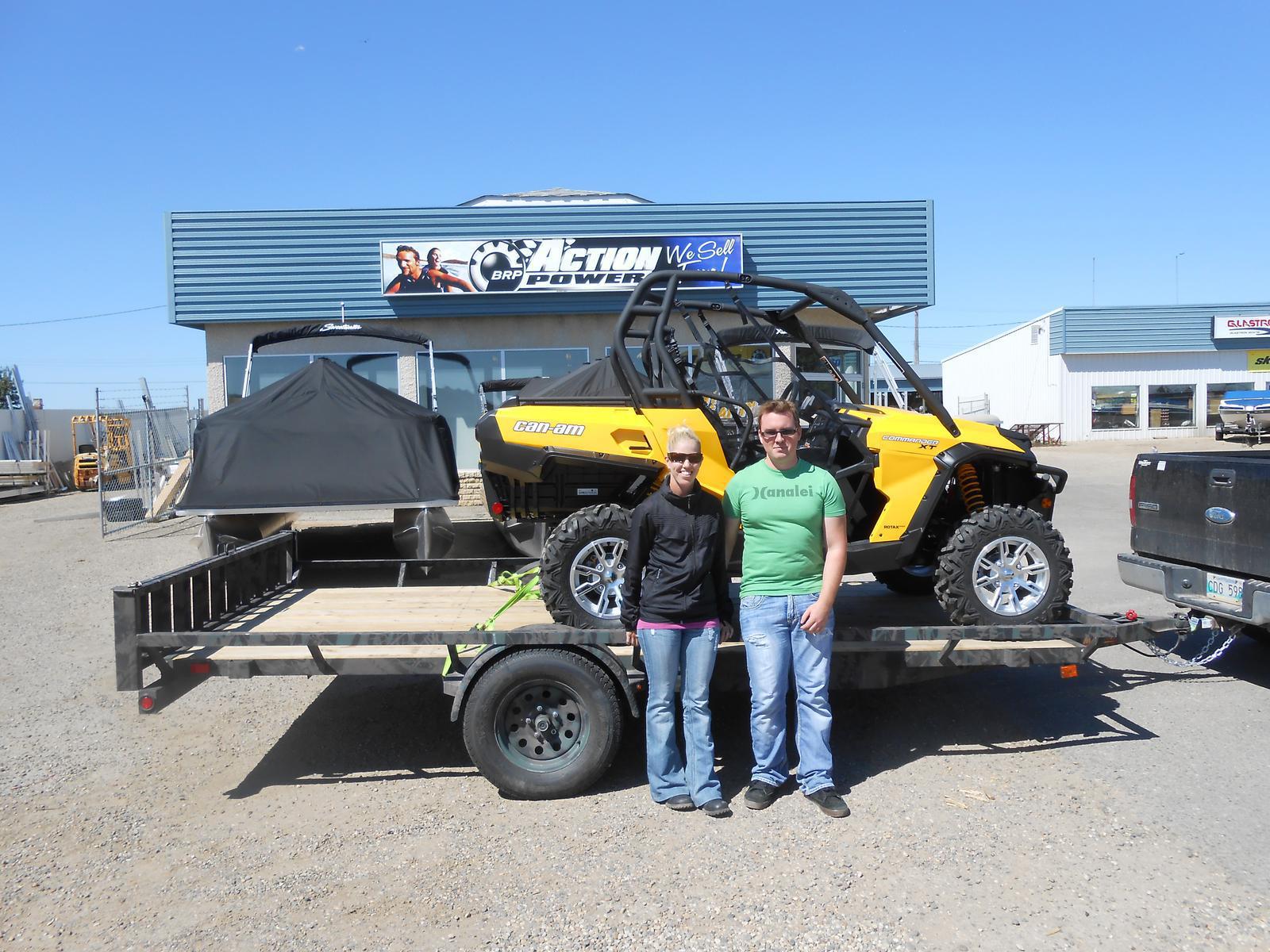 A man and a woman standing in front of a yellow Can-Am Commander XT UTV.
