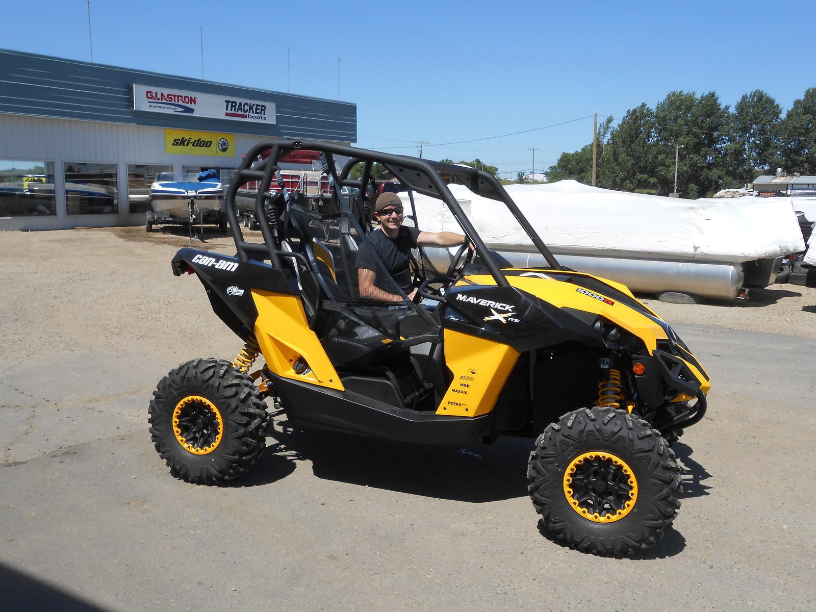 A man seated in a yellow Can-Am Maverick XRS side by side vehicle.