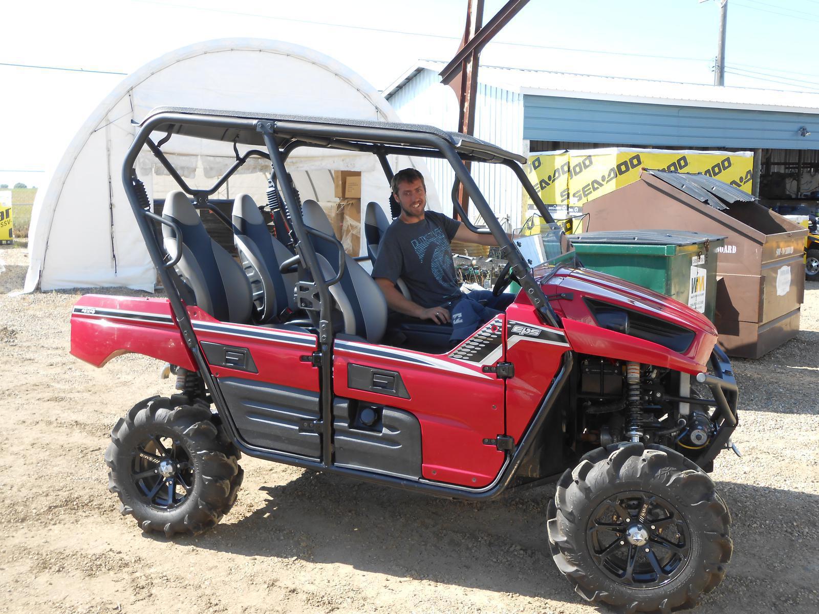 Man seated in a red four-seat side-by-side UTV outside a dealership 