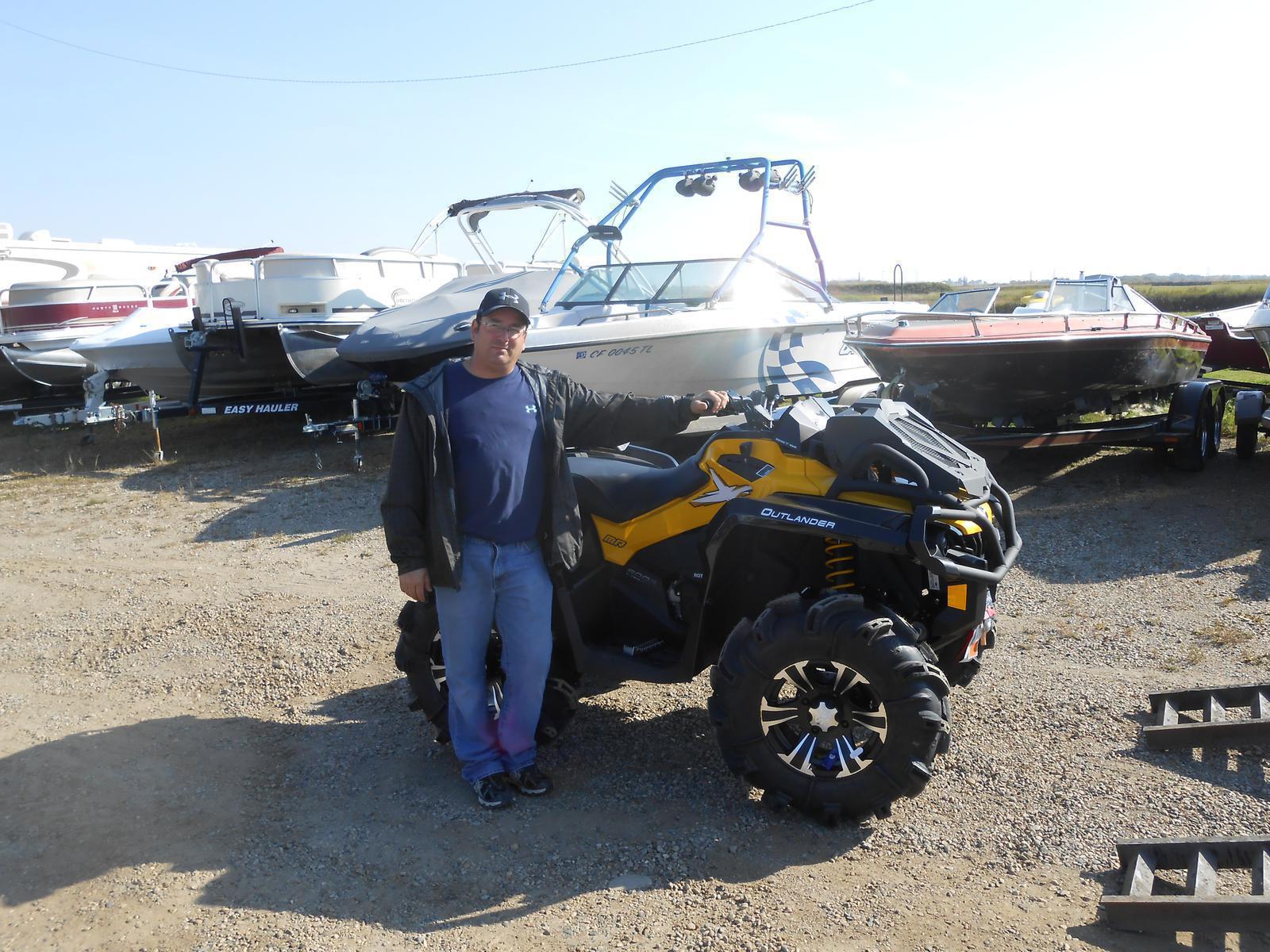 Man posing in front of a black Can-Am Outlander ATV with yellow accents.