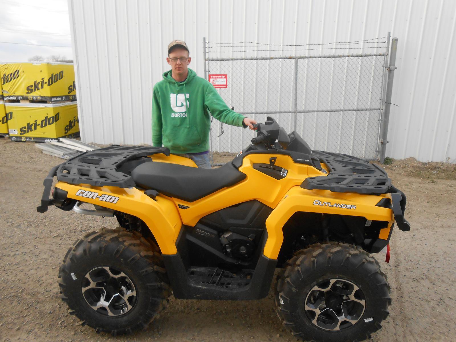 Man posing behind a yellow Can-Am Outlander ATV.