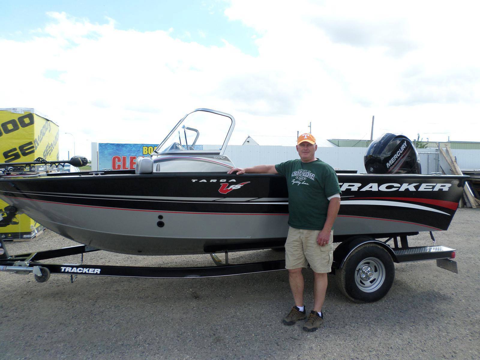 Man posing in front of a black Tracker Targa V16 boat