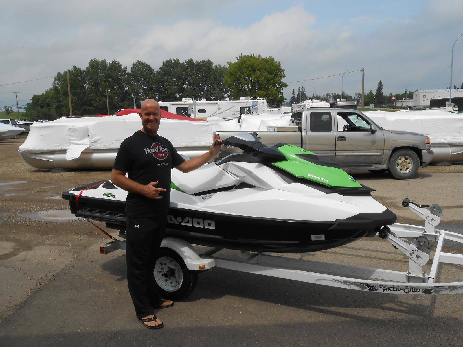 Man standing in fron of a white Sea-Doo GTI watercraft with green accents.