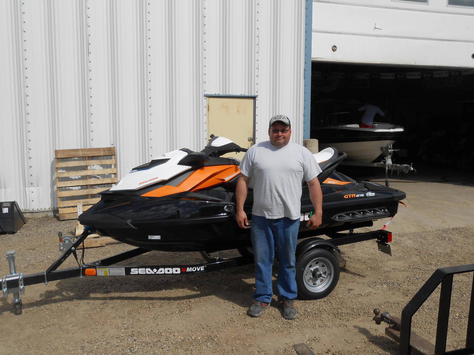 Man standing in front of a Black Sea-Doo GTR watercraft with orange and white accents.