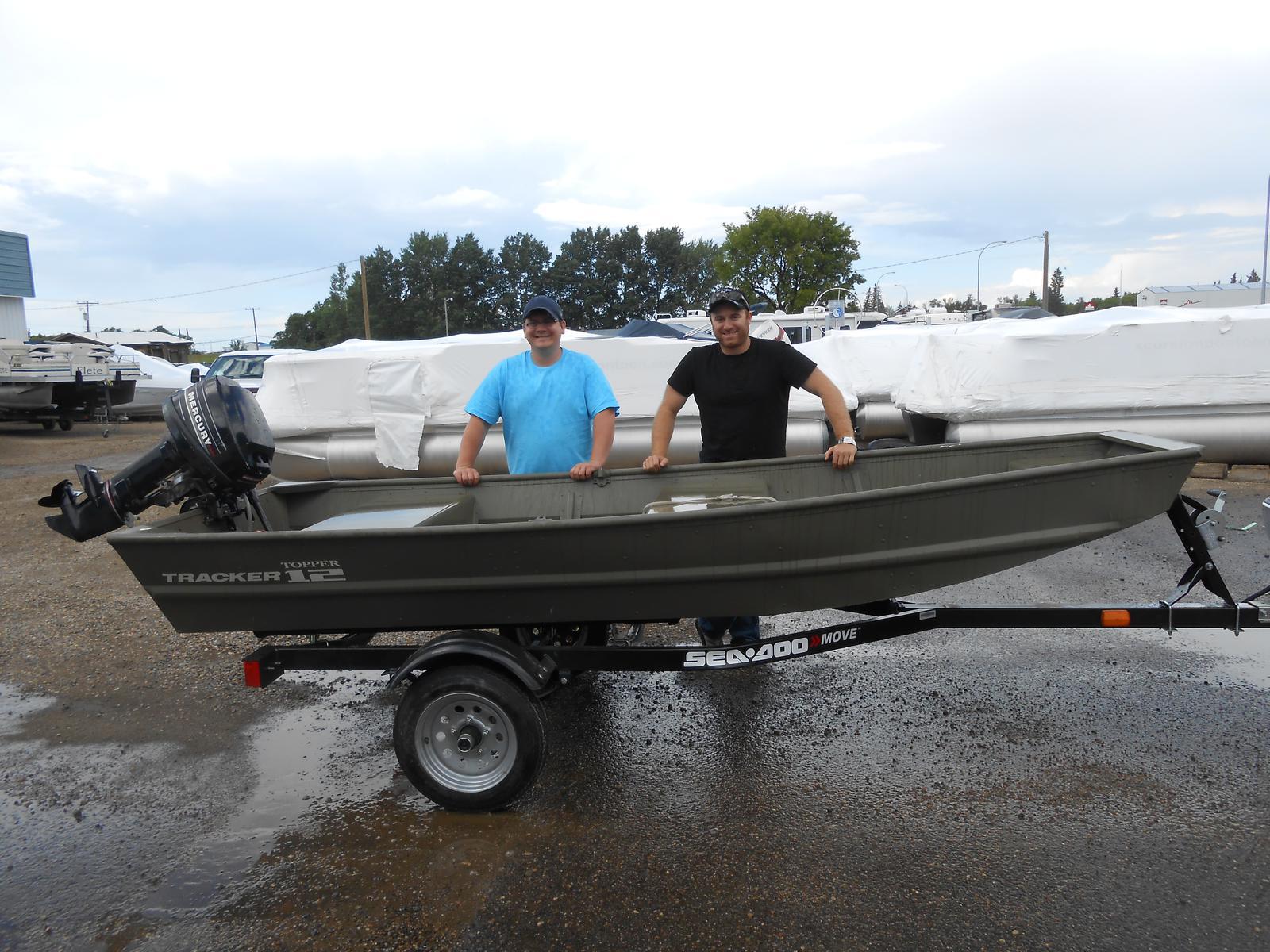 Two men standing behind a gray Tracker Topper 12 Boat